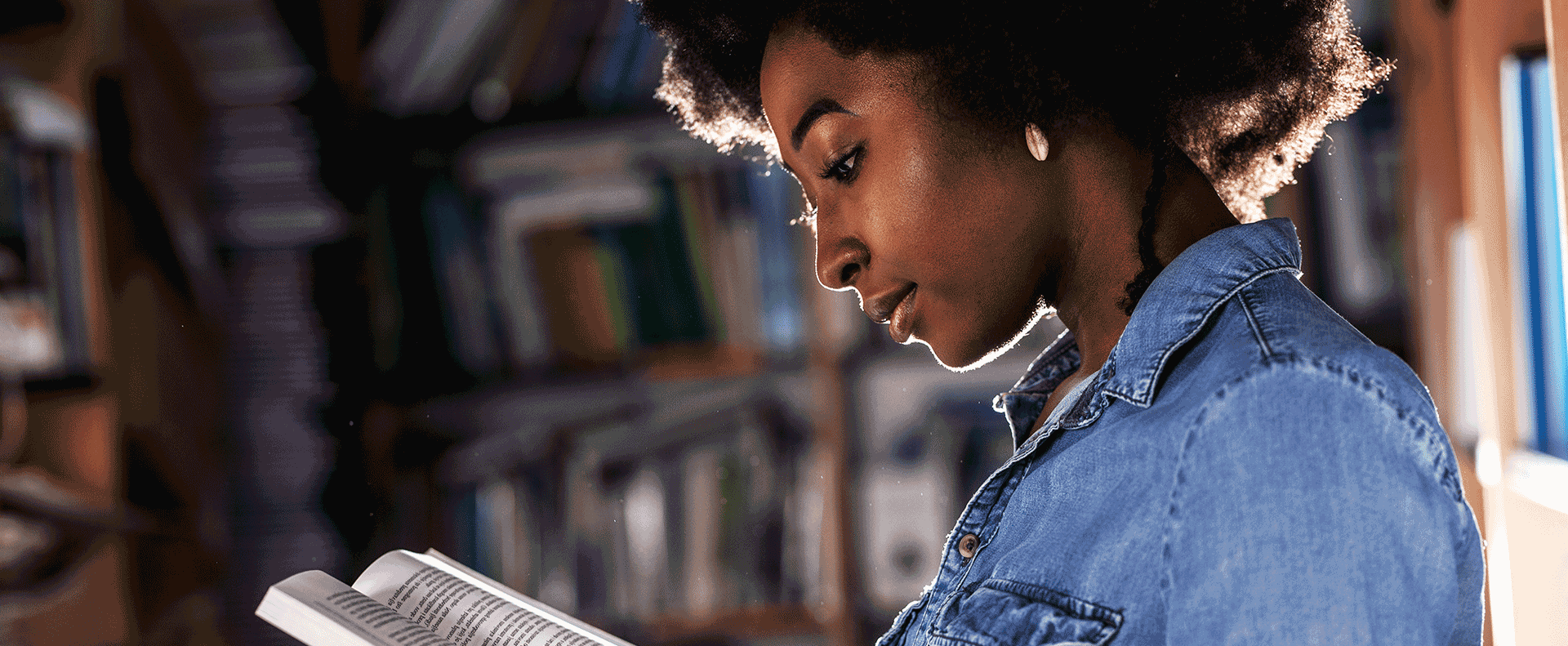 A woman studying the Bible in a library as a student of Aidan University.